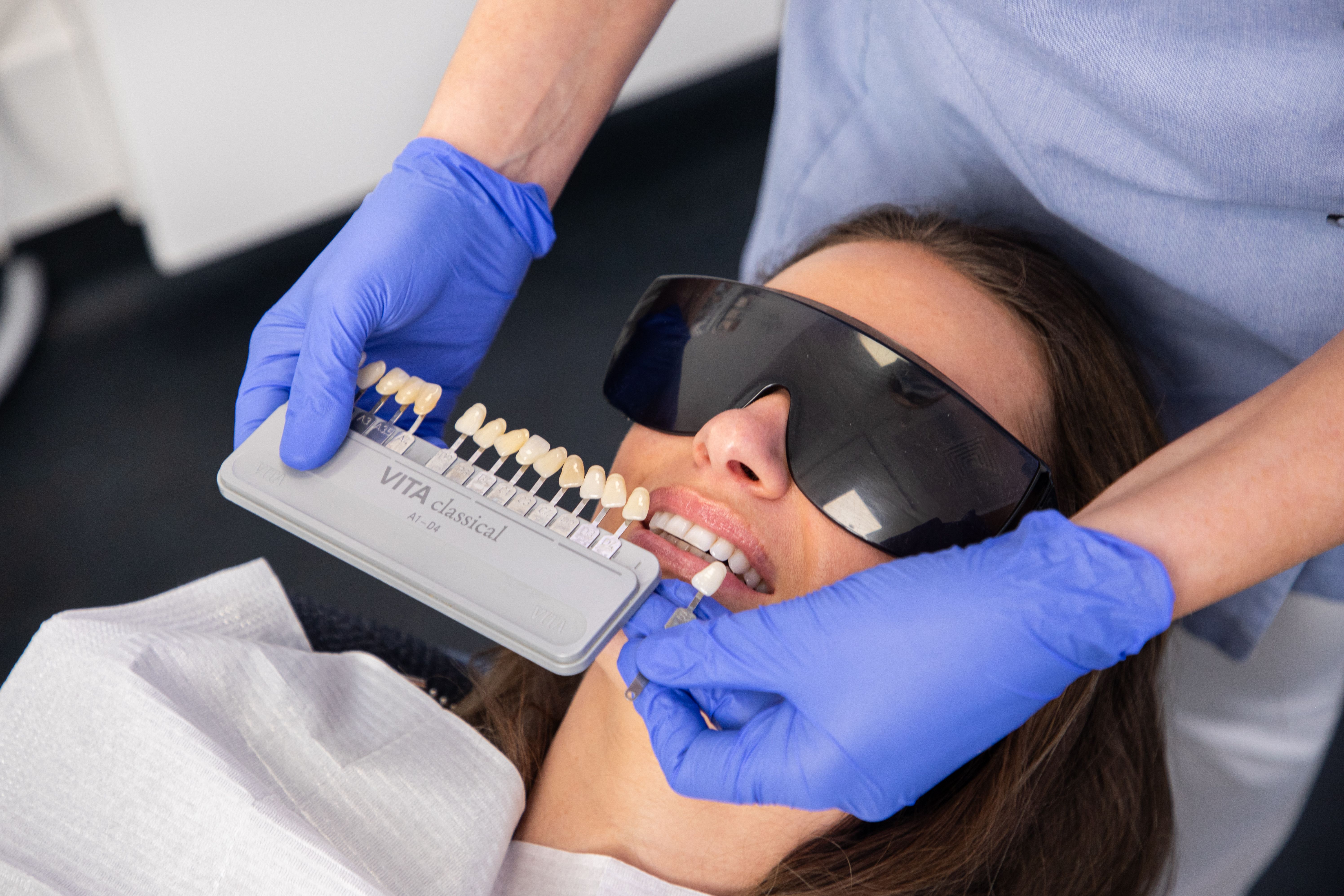 Dental professional matching a tooth shade guide to a patient's teeth.