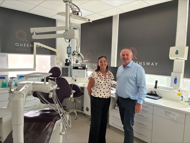 a man and a woman are standing in a dental office .