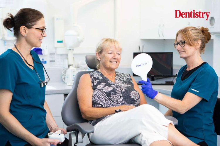 a woman is sitting in a dental chair looking at her teeth in a mirror .