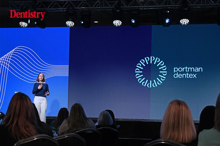 a woman is standing on a stage giving a presentation to a group of people .