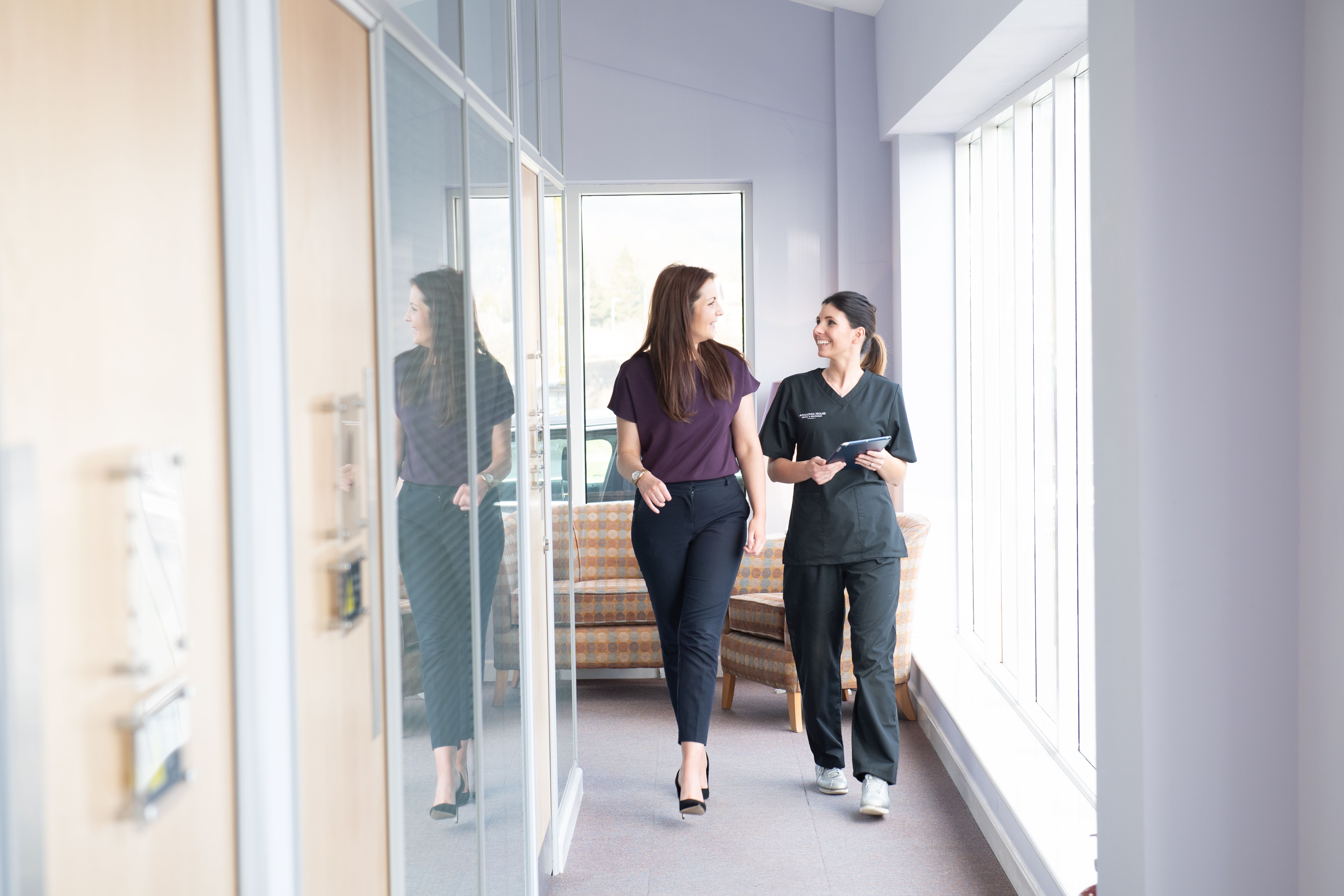 two women are walking down a hallway in a hospital .