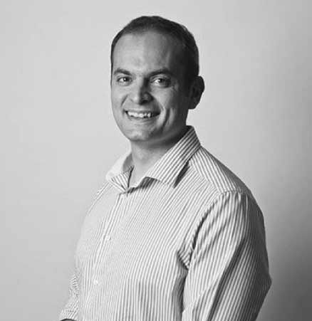 a man in a striped shirt is smiling in a black and white photo .