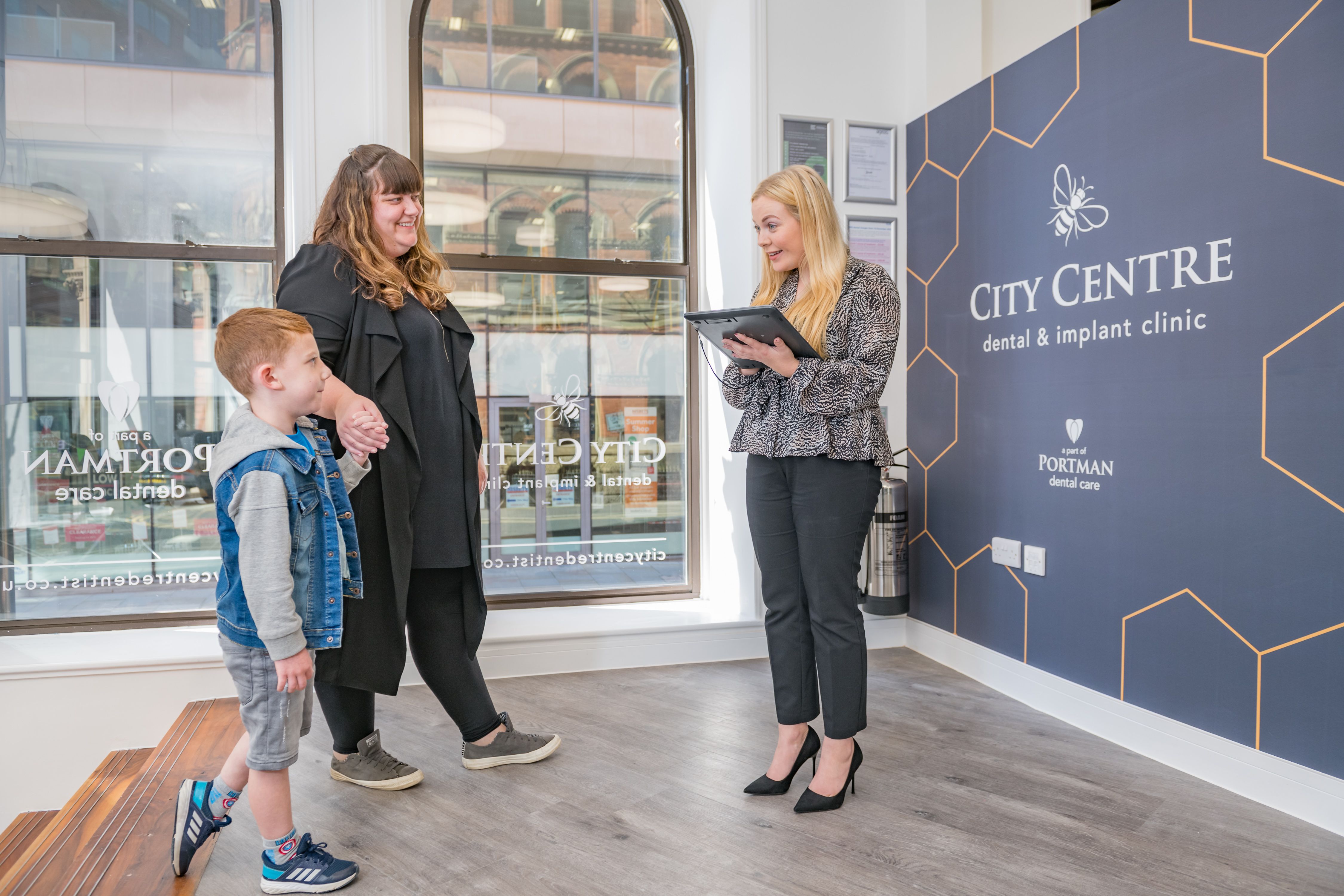 a woman and a child are standing next to each other in a dental office .