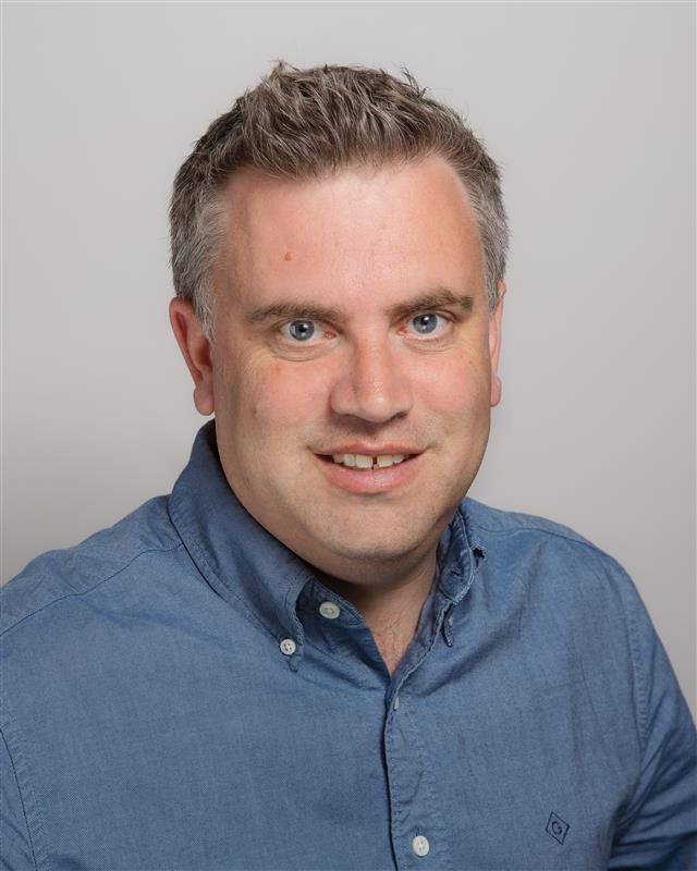 a man wearing a blue shirt with the letter g on it