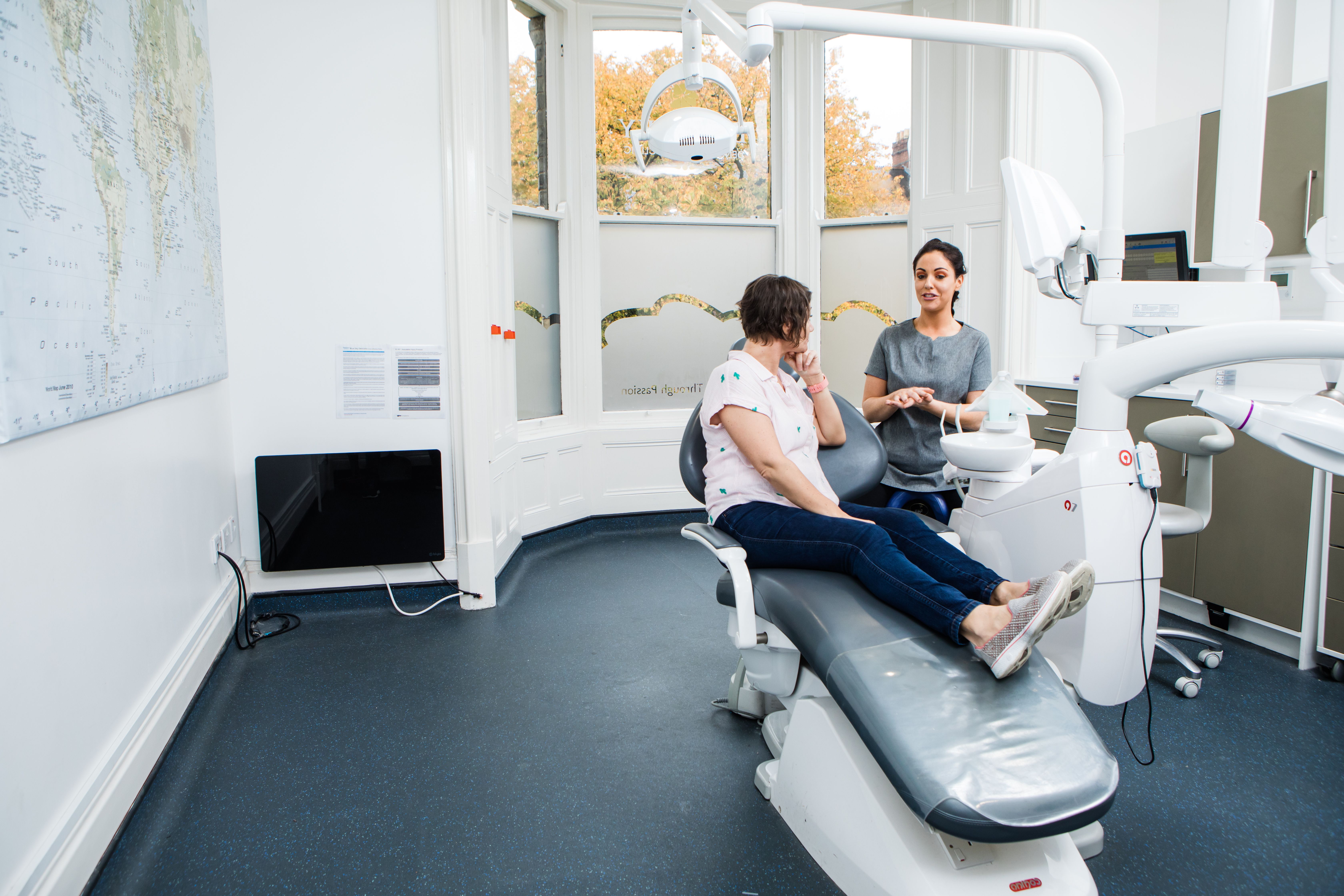 a woman is sitting in a dental chair talking to a dentist .